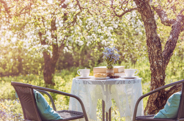 istock Springtime in garden. Table set with tea cups, boho reuse jar vase with forget me not flowers( Myosotis) and small stack of books. Summer relax readings concept. 1269154973