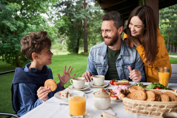 istock Happy parents chatting with son while having breakfast outdoors 1269156837