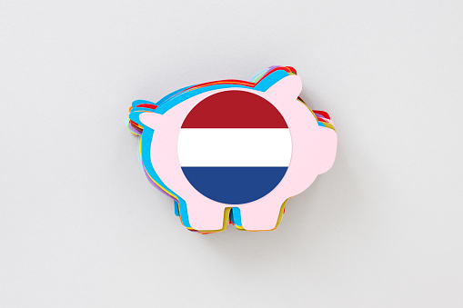 Lots of paper cut piggy bank shapes on top of each other with a dutch flag on them