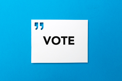 White card with quotation mark where VOTE is written on blue background.