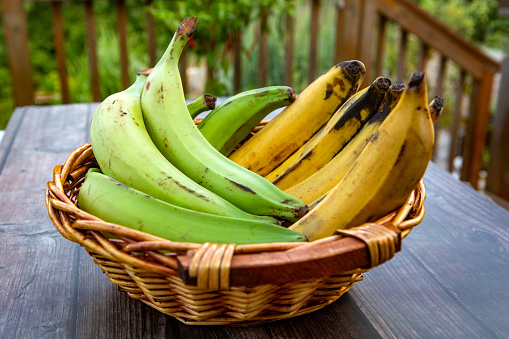 a wicker basket full of yellow and green plantains