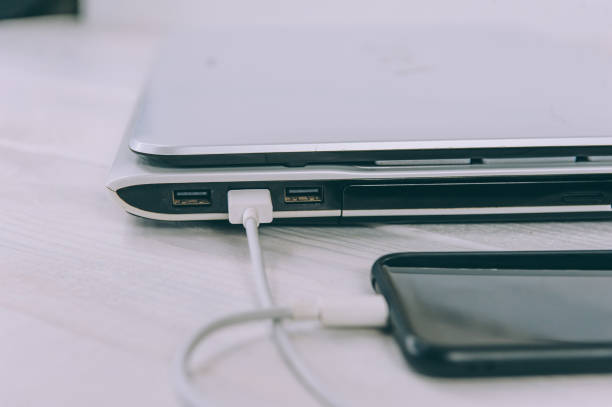 istock The smartphone is charging from a laptop, on a white, wooden table. 1269167775