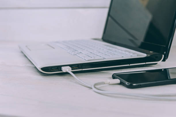 istock The smartphone is charging from a laptop, on a white, wooden table. 1269167779