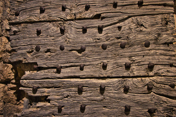 Séguret, France - August 22, 2020. View of a wooden door dating from the 14th century. in the foreground, part of the door, never restored since its manufacture, is visible. on the wood, forged nails also dating back several hundred years are visible.