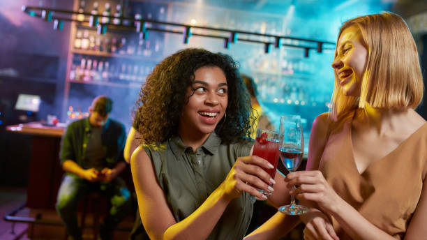 istock Attractive young women looking at each other while toasting, posing with cocktail in their hands. Friends celebrating, having fun in the bar 1269172129