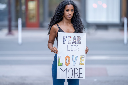 Strong black woman holding up a protest sign that reads, 