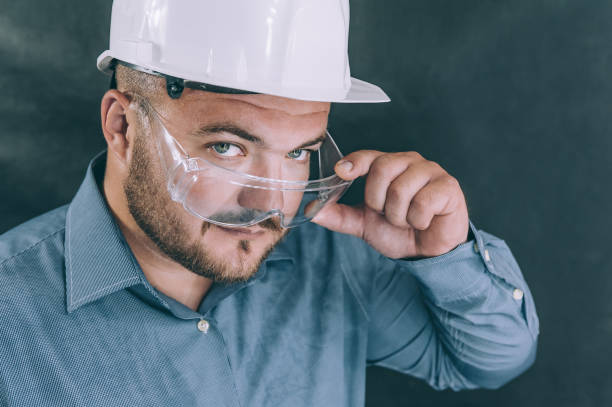 istock A man in safety glasses and a construction helmet on a dark background. 1269174672