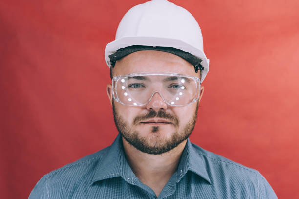 istock A man in safety glasses and a construction helmet on a red background. 1269174675