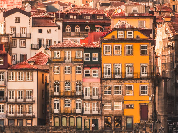 This photo was taken in Porto, Portugal. It shows some iconic yellow buildings with white windows on the bank of the Río Douro.