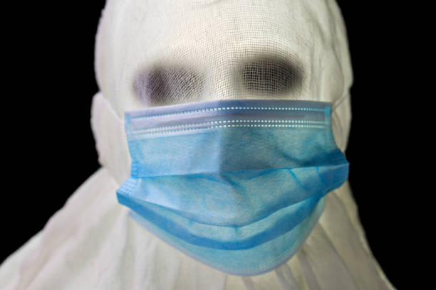 A mummy wears a disposable face mask on halloween.