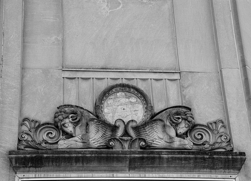 Patinaed stone rams heads top a building's entrance.