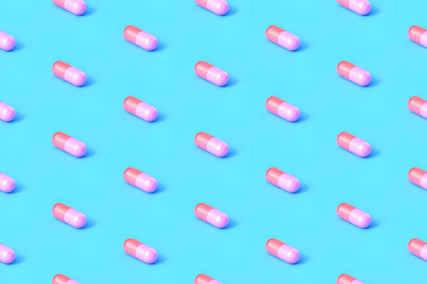 píldoras de cápsulas repetitivas sin costuras sobre fondo azul - pink pill fotografías e imágenes de stock