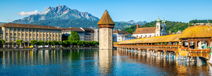 Scenic panoramic view of Lucerne with Chapel bridge or Kapellbrucke and Pilatus mount with clear blue sky during summer in Lucerne old town Switzerland