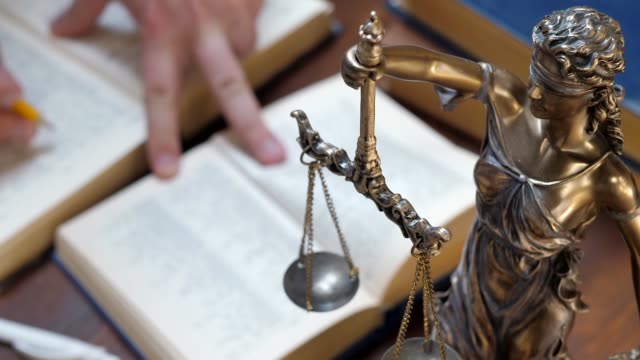 Unrecognizable lawyer's hand works with papers and law books