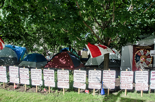 Tents of people demonstrating against Canada Federal Government in Ottawa during summer day. All theirs demands are written on signs long their camp