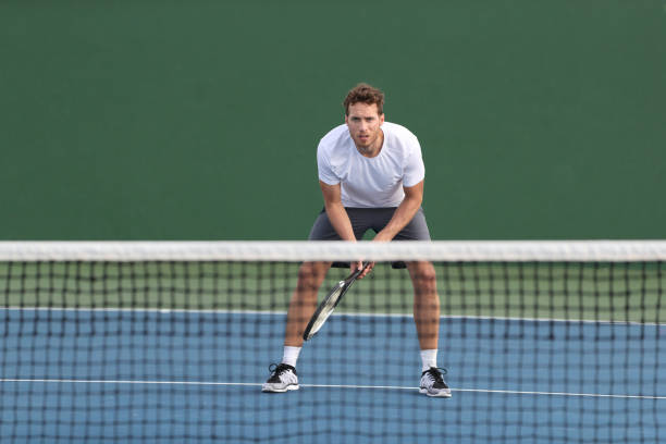 ハードコートでゲームをして、ボールを受け取るのを待っているプロテニス選手の男の選手。フィットネスの人は、屋外スポーツ活動にトレーニングカーディオを返す準備ができてネットの� - tennis court sports training tennis net ストックフォトと画像