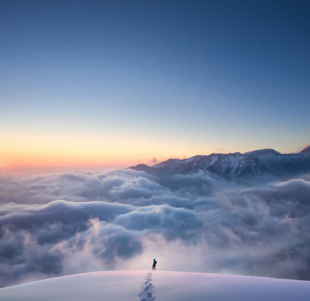 Above The Fog Man hiking through fresh snow above the fog. Idyllic winter mounatin landscape at sunset. footprint photos stock pictures, royalty-free photos & images
