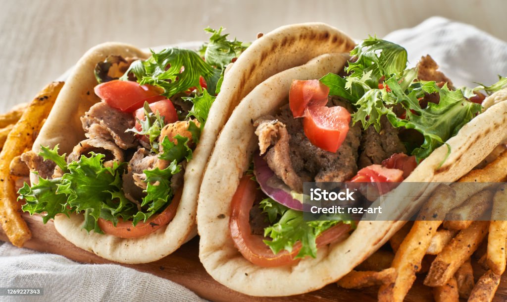 two greek gyros with fries, tomato and lettuce two Greek gyros with fries, tomato and lettuce close up Gyro - Food Stock Photo