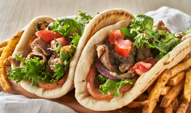 two greek gyros with fries, tomato and lettuce two Greek gyros with fries, tomato and lettuce close up flatbread photos stock pictures, royalty-free photos & images