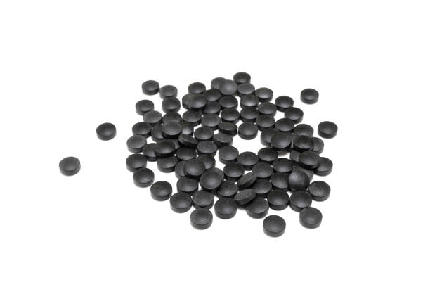 istock Round black pills of iron on a white background. SUPPLEMENT 1269236955