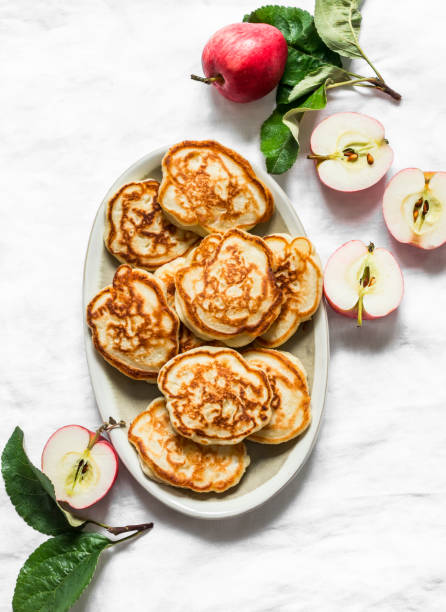 This is a photograph of a large tall stack of pancakes on a pink background