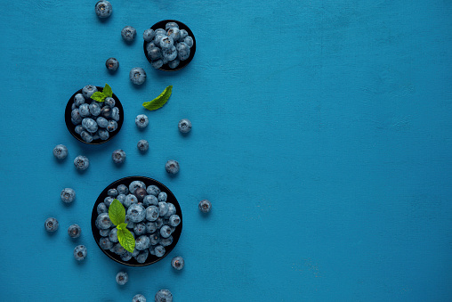 Tasty fresh blueberries in bowls on light grey table, closeup