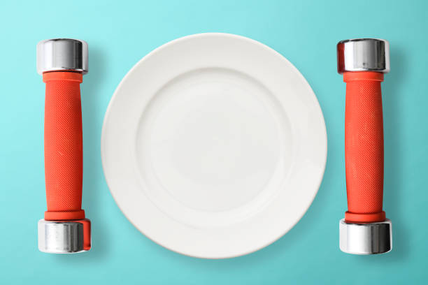 Red dumbbells beside white plate on light blue background