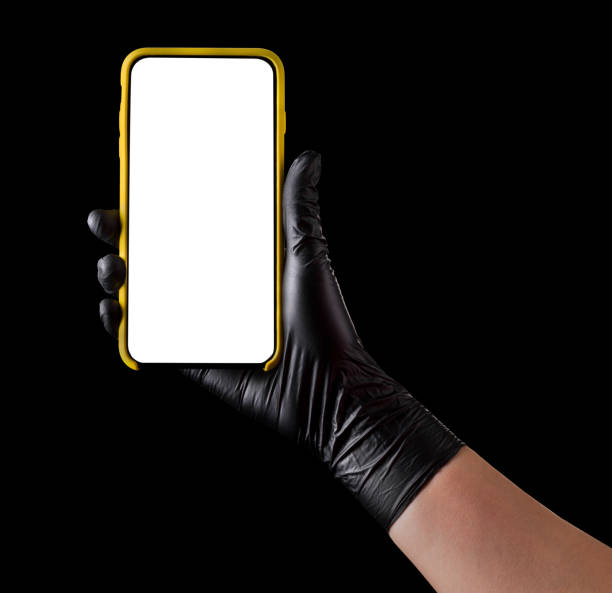 istock Hand in black glove holding mobile phone with blank screen isolated on black 1269247521