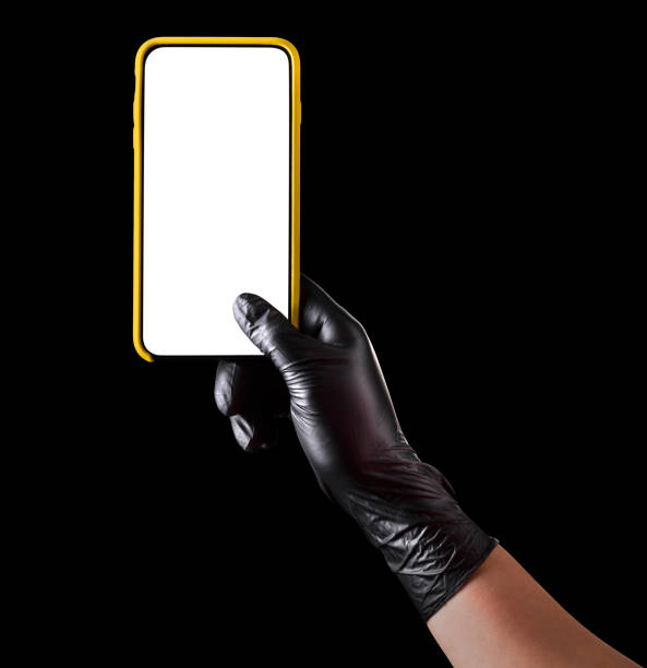 istock Hand in black glove holding mobile phone with blank screen isolated on black 1269247543