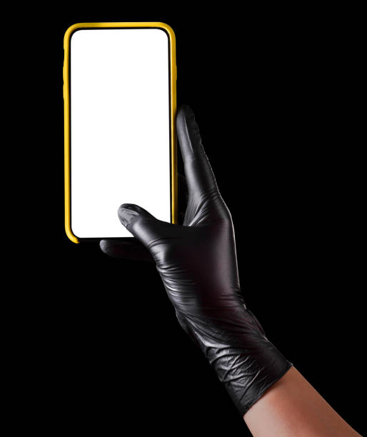 istock Hand in black glove holding mobile phone with blank screen isolated on black 1269247552