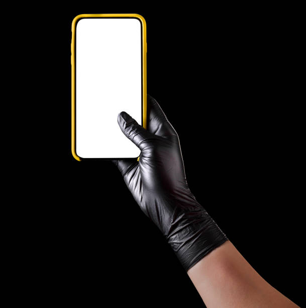 istock Hand in black glove holding mobile phone with blank screen isolated on black 1269247576