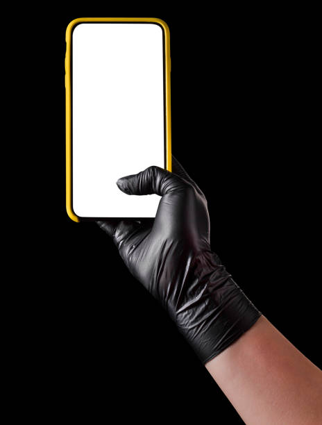 istock Hand in black glove holding mobile phone with blank screen isolated on black 1269247579