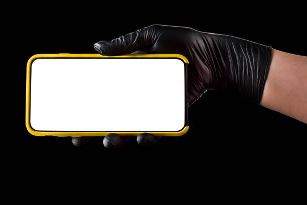 istock Hand in black glove holding mobile phone with blank screen isolated on black 1269247585