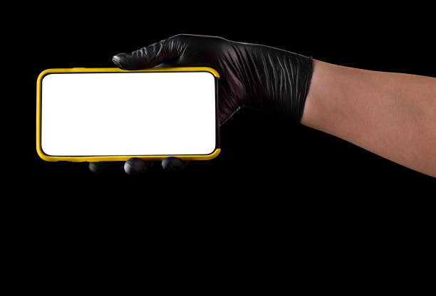 istock Hand in black glove holding mobile phone with blank screen isolated on black 1269247588