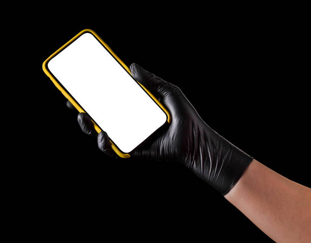 istock Hand in black glove holding mobile phone with blank screen isolated on black 1269247598