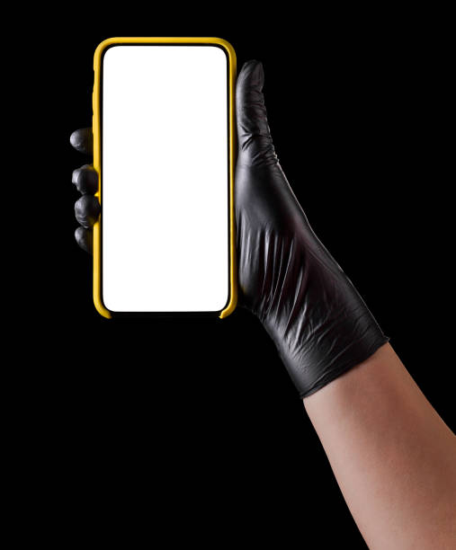 istock Hand in black glove holding mobile phone with blank screen isolated on black 1269247600
