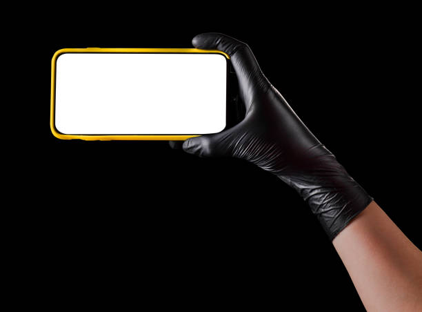 istock Hand in black glove holding mobile phone with blank screen isolated on black 1269247620