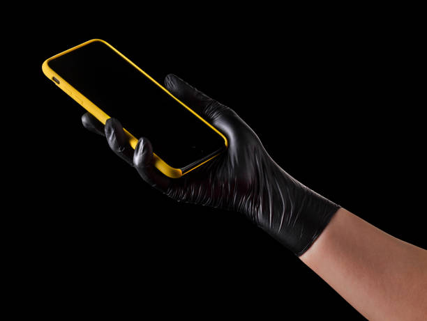 istock Hand in black glove holding mobile phone with blank screen isolated on black 1269247622