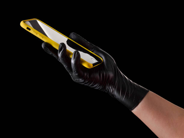 istock Hand in black glove holding mobile phone with blank screen isolated on black 1269247627