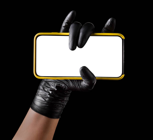 istock Hand in black glove holding mobile phone with blank screen isolated on black 1269247649