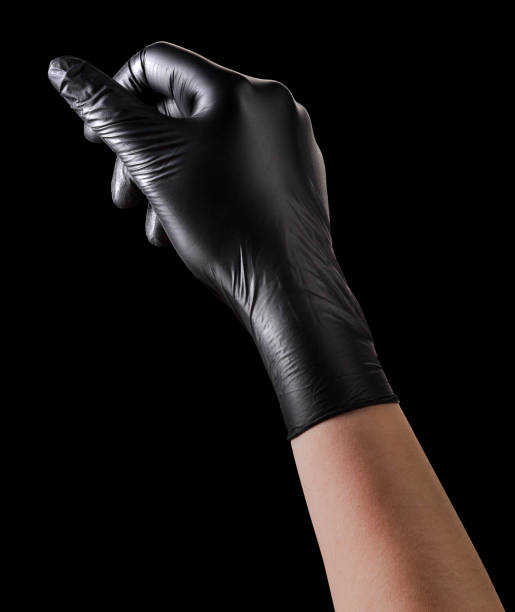 рука в черной перчатке, держащая что-то изолированное на черном фоне - glove leather black isolated стоковые фото и изображения