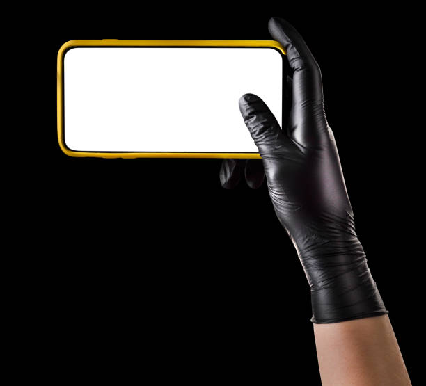 istock Hand in black glove holding mobile phone with blank screen isolated on black 1269247699