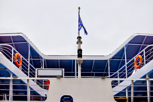 Top deck of ship with National Greek flag waving in the wind. Stock image.
