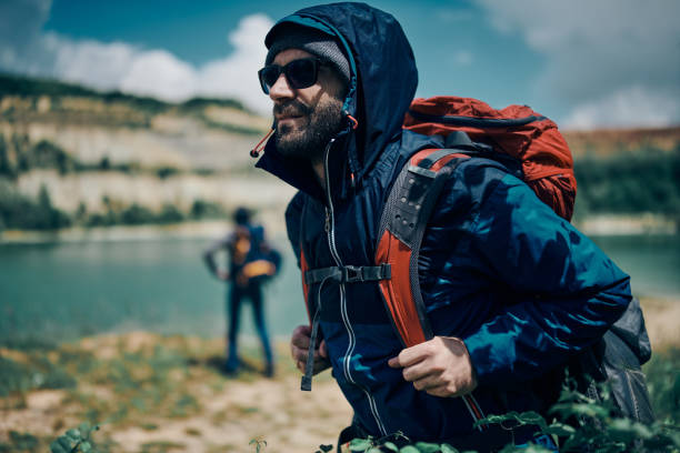 istock Attractive bearded man holding his backpack and exploring nature on a camping trip. 1269247870