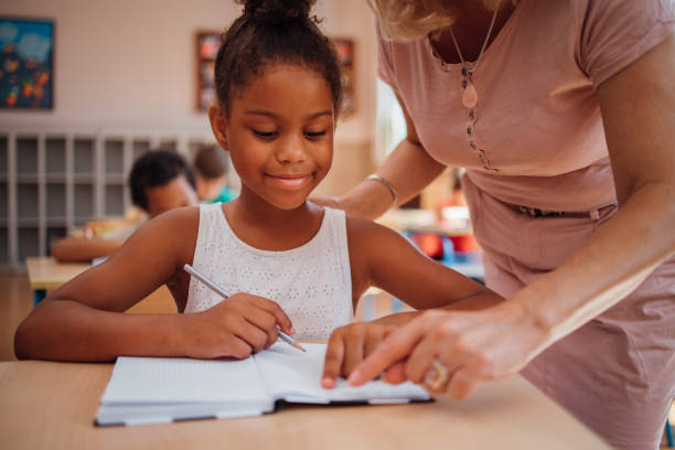 istock Teacher helping to a schoolgirl with assignment 1269250257
