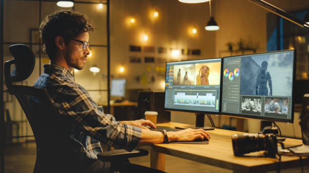 istock Late Evening Creative Office: Professional Colorist / Photograph Works on a Desktop Computer, Doing Photo Montage, Using Image Editing Software. Modern Stylish Office Environment 1269257001