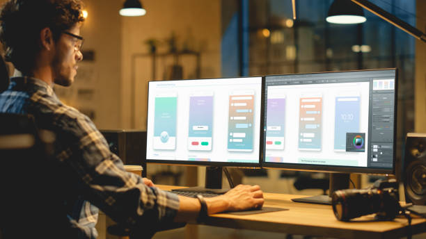 深夜クリエイティブオフィス:プロのプログラマーは、編集ソフトウェアを使用して、電話アプリのデザインを作成し、デスクトップコンピュータ上で動作します。モダンスタイリッシュオフ - colorist ストックフォトと画像