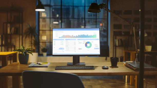 istock Shot of a Desktop Computer with Statistics Graph, Chart and Various Data, Showing Company Growth and Success. In the Background Warm Evening Lighting and Open Space Studio with City Window View. 1269257098