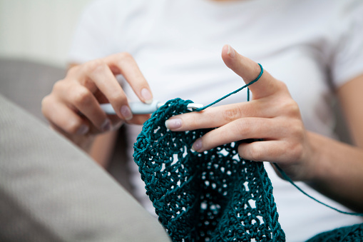 Low angle view of a teenager doing crochet with selective focus on the hands