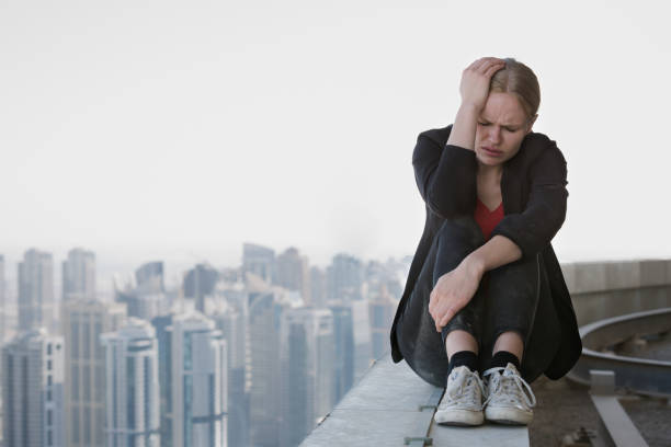 triste giovane donna seduta sul bordo di un grattacielo con la vista della città. stress e fallimento del lavoro. - suicide skyscraper anxiety at the edge of foto e immagini stock